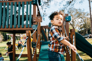 Young boy standing on the ramp of a playset.