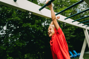 Young boy climbing across the monkey bars on a playset.