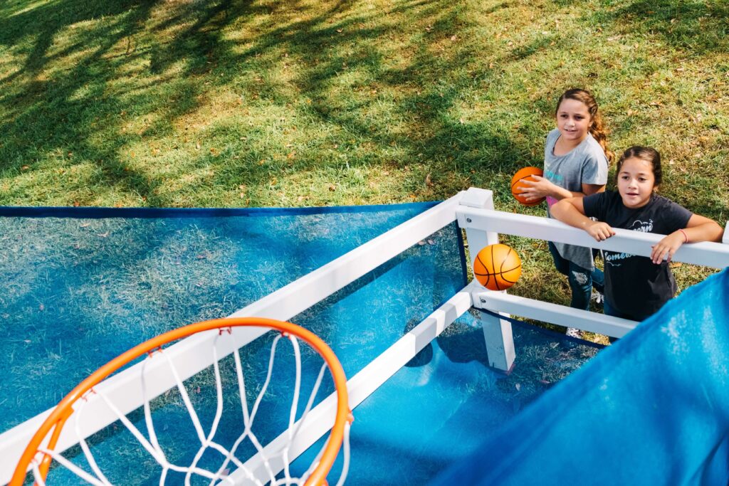 2 girls playing on a swing kingdom buzzer beater hoops attachment