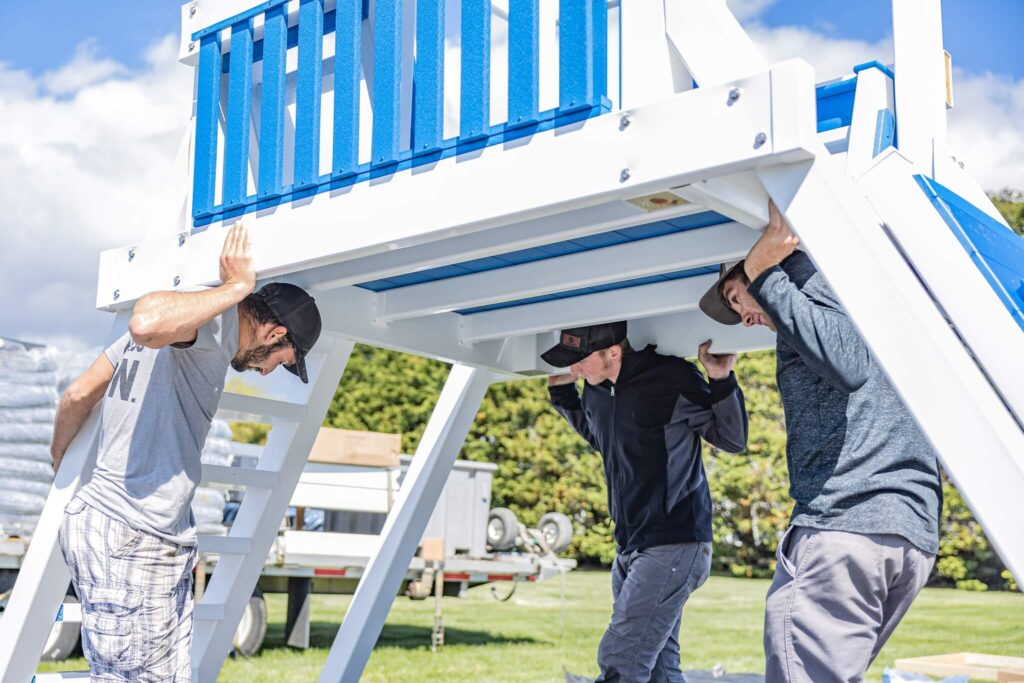 3 swing kingdom workers delivering a playset to a customer's backyard