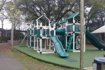green and white commercial playset with lots of towers and slide options