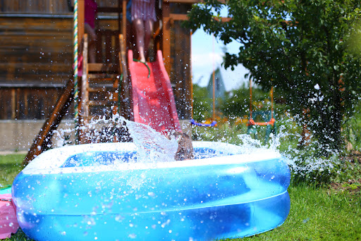 an inflatable pool positioned at the end of a slide to make a waterslide at home