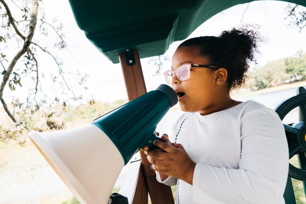 girl using a megaphone attachment on a playset