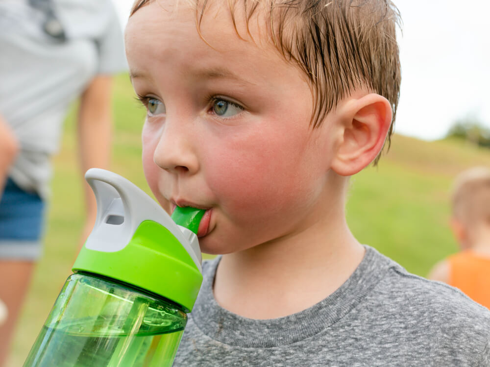 young sweaty boy drinking form a water bottle