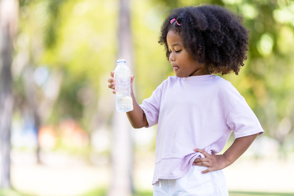 young girl standing with a plastic water bottle in hand