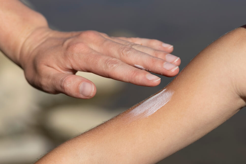 close up of mother rubbing sunscreen in on her child's arm