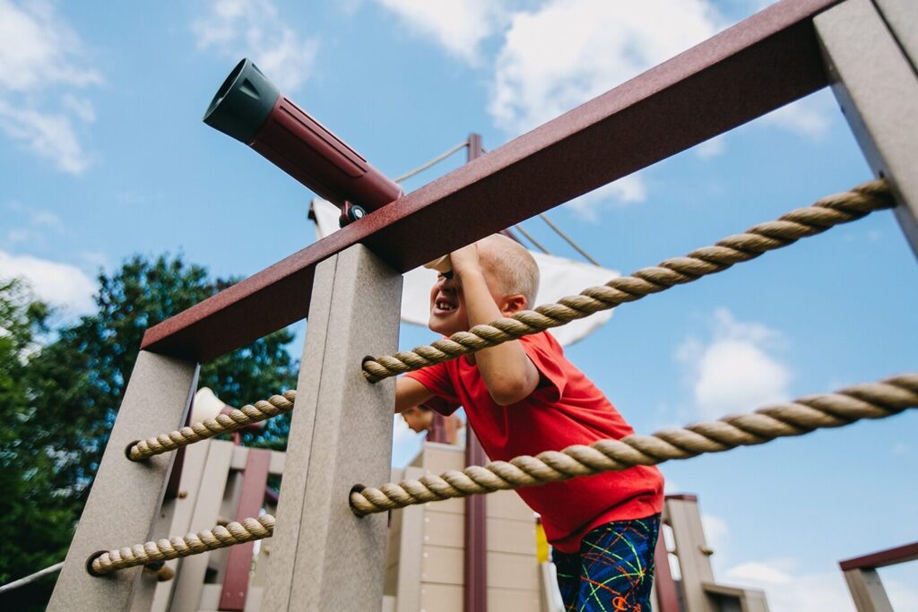 Young boy looking out a telescope accessory on a commercial playset.