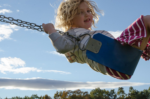 young girl swinging on her own