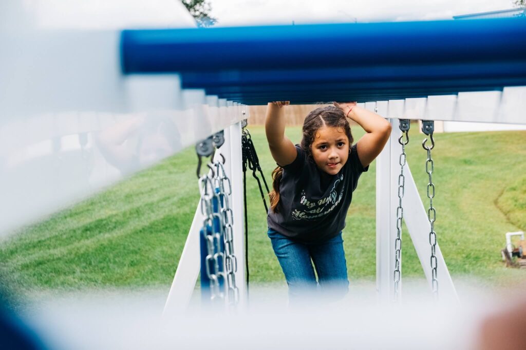 a girl going across monkey bars on a playset